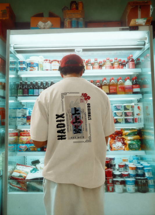 Mann steht vor einem Kühlschrank und wählt sein Getränk trägt Hadix Oversized T-Shirt mit asiatischen Schriftzügen gut rich or die trying
